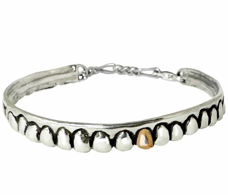Silver tooth bracelet with  gold accent tooth on a white background