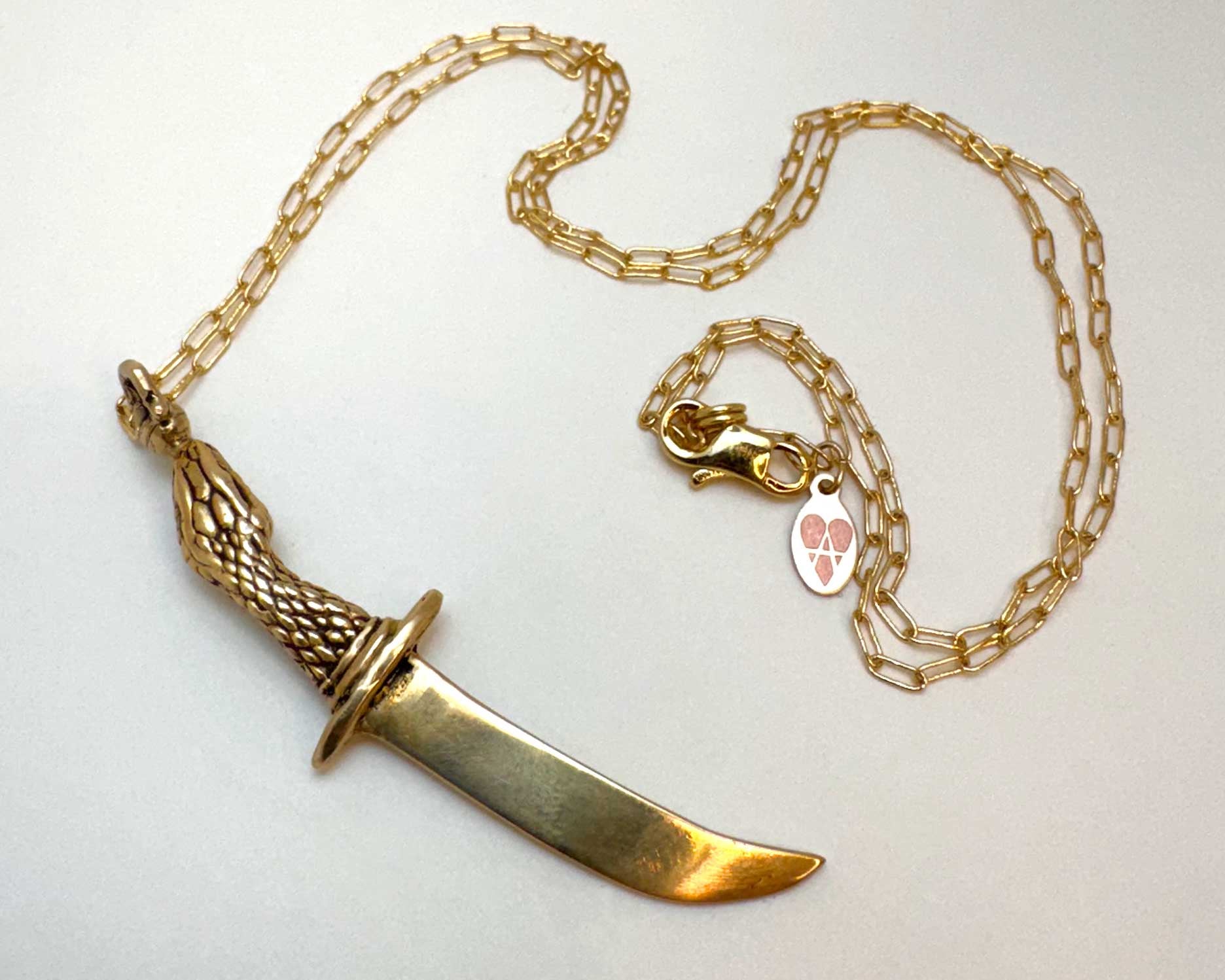 Gold snake knife-shaped pendant on a chain necklace with a visible brand logo on a white background